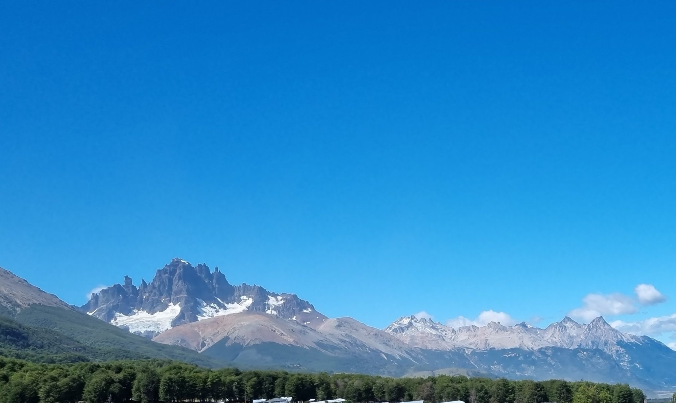 Jagged granite peaks with glaciers under a clear blue sky