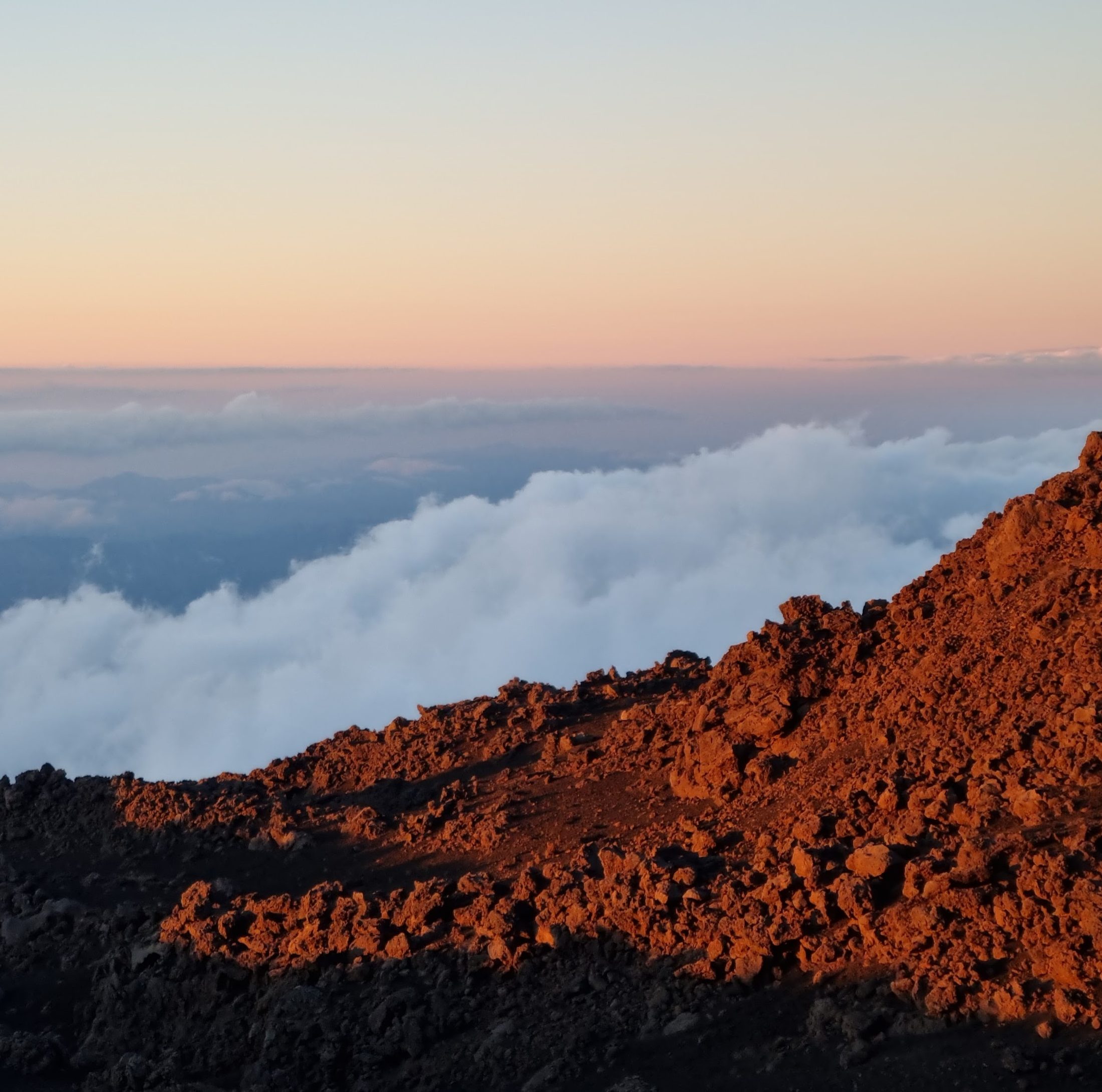 Mountain ridge rising above a sea of clouds at sunrise