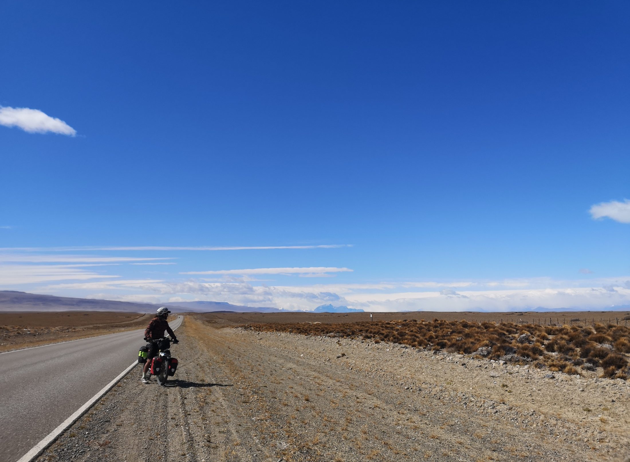 A loaded touring bicycle on a long empty road across the Patagonian steppe